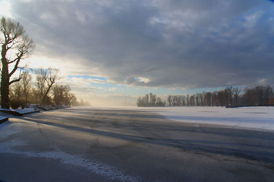 Snow covered landscape against cloudy sky