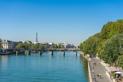 Bridge over river in city against clear blue sky