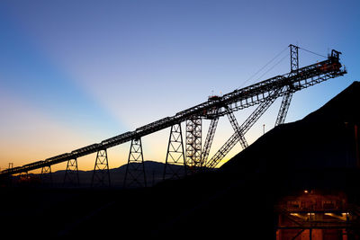 Low angle view of silhouette cranes against sky during sunset