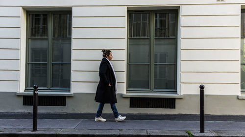 Side view full length of woman walking outside building on sidewalk