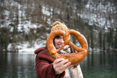 Woman in winter clothes holding a pretzel.