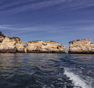 Rock formations in sea against blue sky