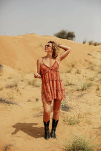 A lonely girl walks down the sand dunes. a caucasian woman in a short dress 