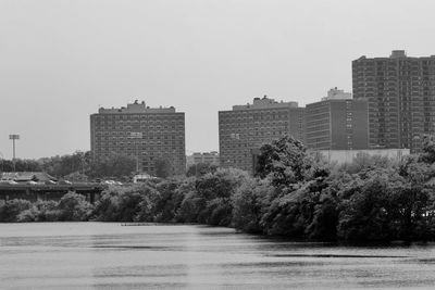 Buildings by river against clear sky