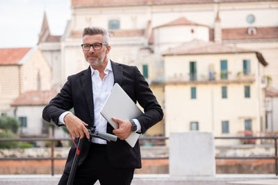 Businessman standing with electric scooter