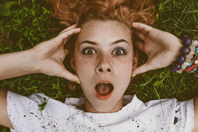 Close-up portrait of shocked woman lying on field