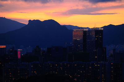 Illuminated buildings in city against sky during sunset