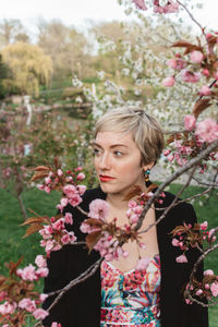 Portrait of woman with pink flowers against trees