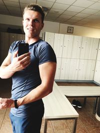 Portrait of man taking selfie against lockers