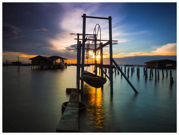 Pier on sea against sky during sunset