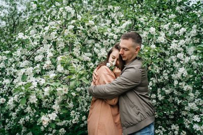 Young couple in love girl and man hugging blooming apple tree aroma of flowers outdoors