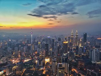 Aerial view of illuminated city against sky during sunset