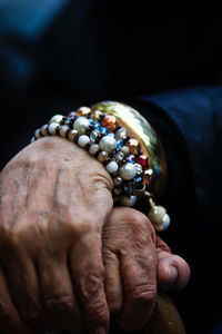 Close-up of person hand holding ring against black background