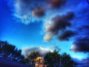 Low angle view of silhouette trees against blue sky