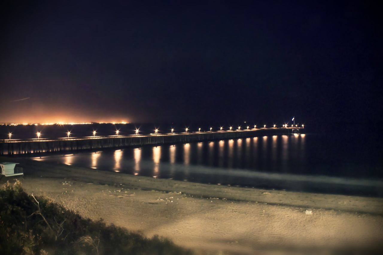 night, illuminated, water, built structure, architecture, reflection, river, bridge - man made structure, copy space, sea, sky, clear sky, connection, beach, city, bridge, street light, outdoors, shore, dusk