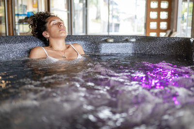 Woman with eyes closed while relaxing in a jacuzzi at a spa.