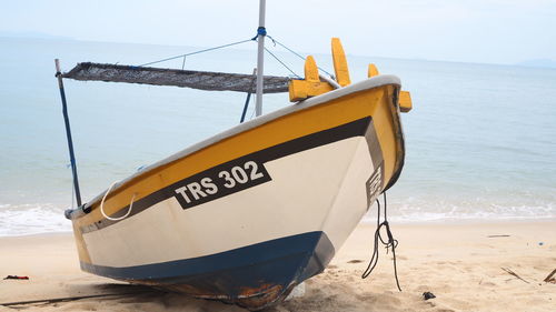 Boat moored on beach against sky