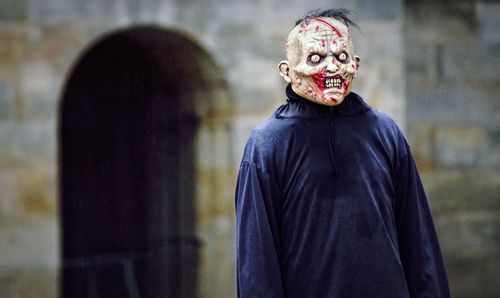 Midsection of person wearing mask against wall