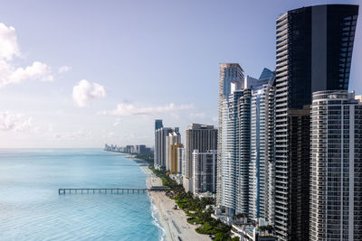 Modern buildings by sea against sky in city