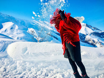 Midsection of person on snowcapped mountain against sky