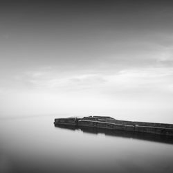 Pier amidst sea against cloudy sky