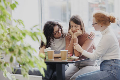 Friends consoling woman in cafe