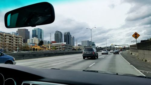 Cars on road against cloudy sky