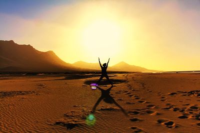 Man on sand at beach against sky during sunset