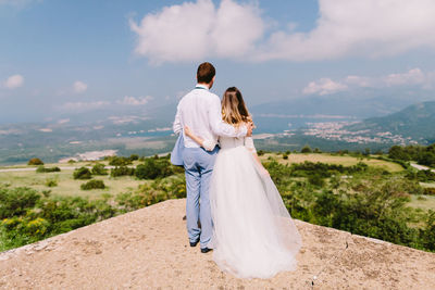 Rear view of married couple standing at observation point against sky