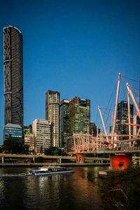Buildings by river against blue sky