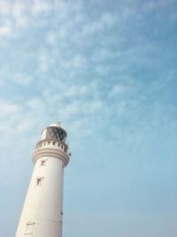 Low angle view of lighthouse by building against sky