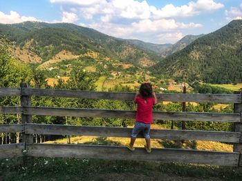 Girl looking at view while standing on fence