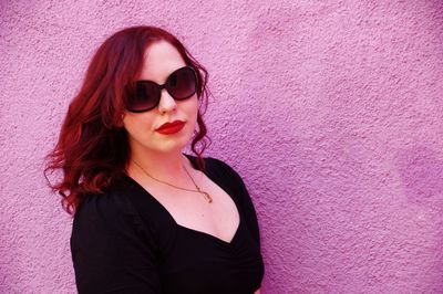 Close-up portrait of young woman against pink background