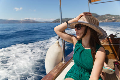 Woman sitting on boat sailing in sea against sky