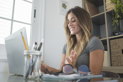 Young woman using mobile phone while sitting on table