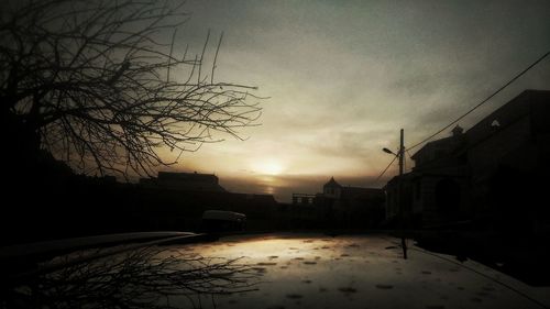 Silhouette of buildings against cloudy sky at sunset