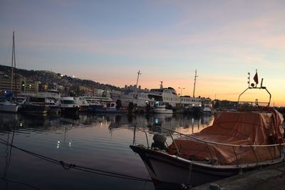 Boats moored at harbor against sky during sunset