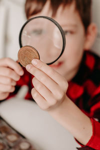 Collecting coins. the boy examines an old coin through a magnifying glass. dollars, euros 