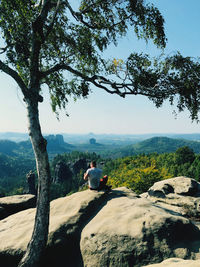 Rear view of people sitting on landscape against sky