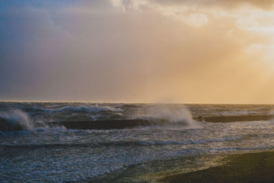 Waves splashing in sea against sky