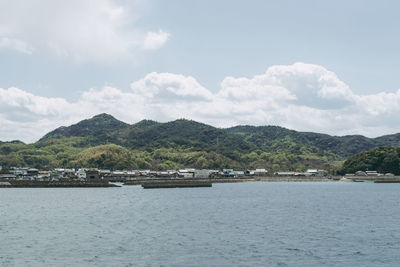 Scenic view of sea by mountains against sky