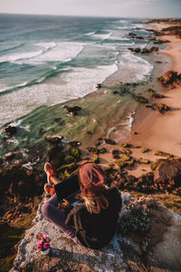 Woman sitting on rock by sea