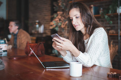 Young woman using laptop on table at cafe