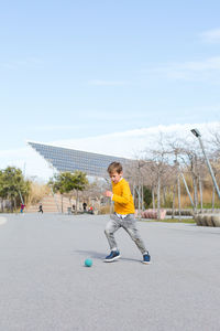 Boy playing with umbrella against sky