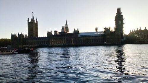 View of buildings by river against clear sky