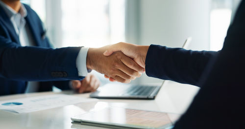 Midsection of business colleagues shaking hands in office