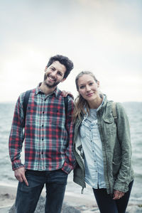 Portrait of young couple standing against sky