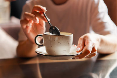 Closeup of female hands with french manicure holding cozy ceramic white mug of tea or coffee. relax