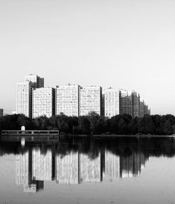 Reflection of buildings in lake against clear sky