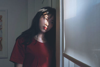 Close-up of young woman standing against wall